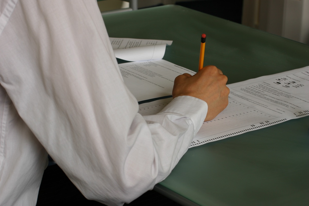 A person writing carefully on an answer sheet during the telc B2 exam